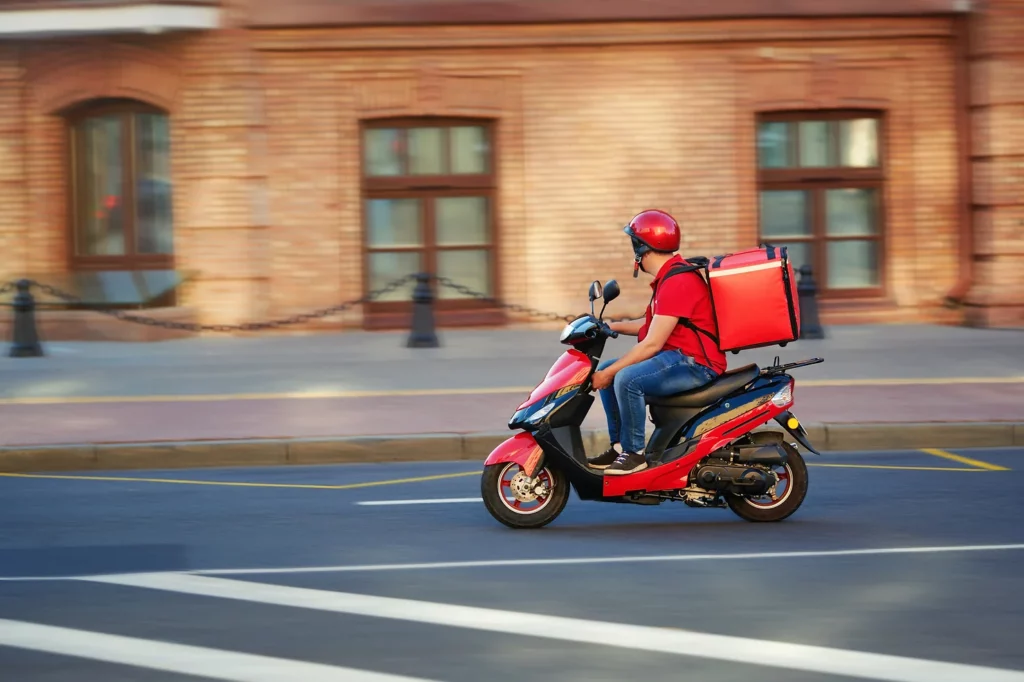 man making a food delivery on a red scooter