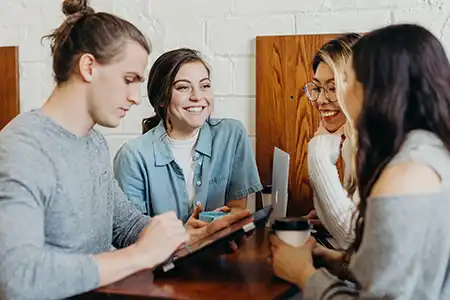 young students sitting around a table laughing