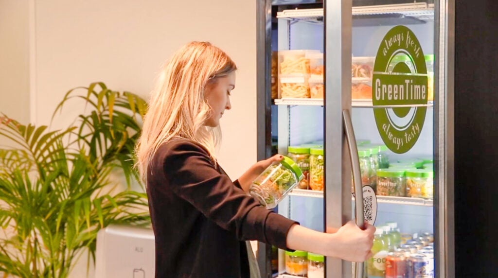 woman looking at a jar of healthy food after pulling it out of a smart cooler
