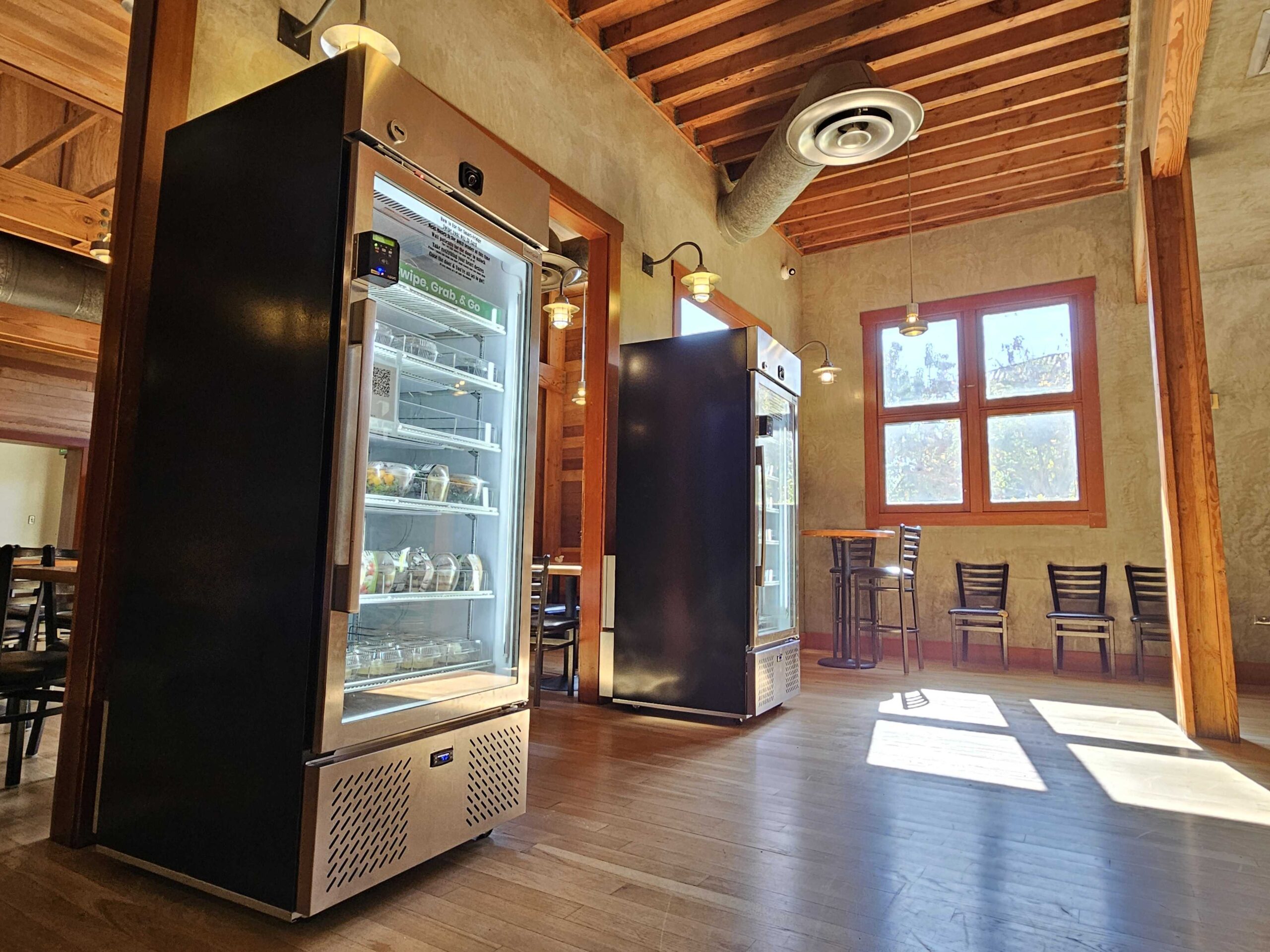 two stainless steel healthy food vending machines in a student cafe seating area