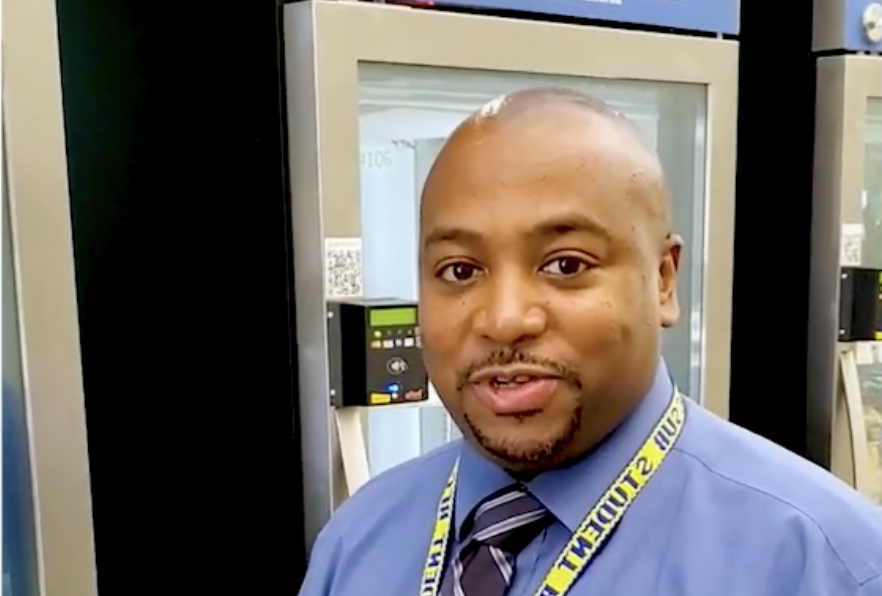 man smiling at camera in front of smart fridge pantry
