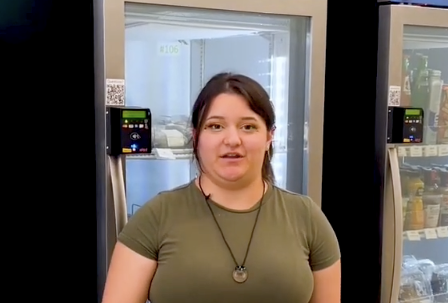 female student at CSU bakersfield smiling in front of smart fridge microstore