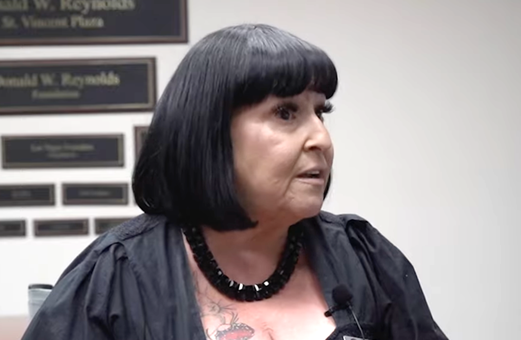 dark haired woman looking off to the right in a corporate conference room