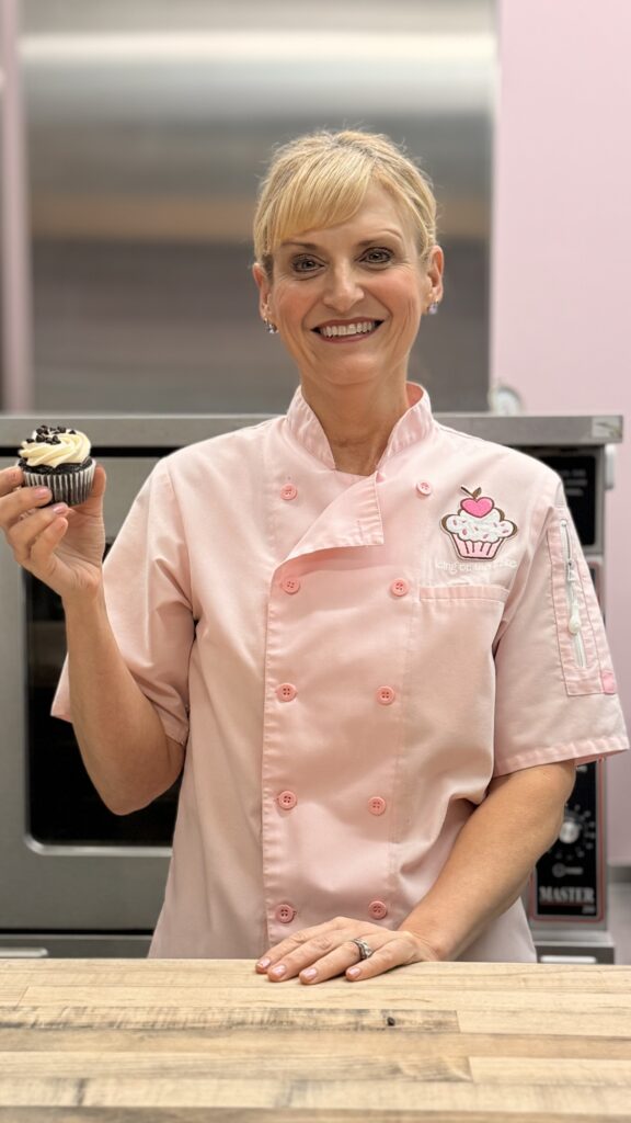 woman smiling at the camera holding a cupcake