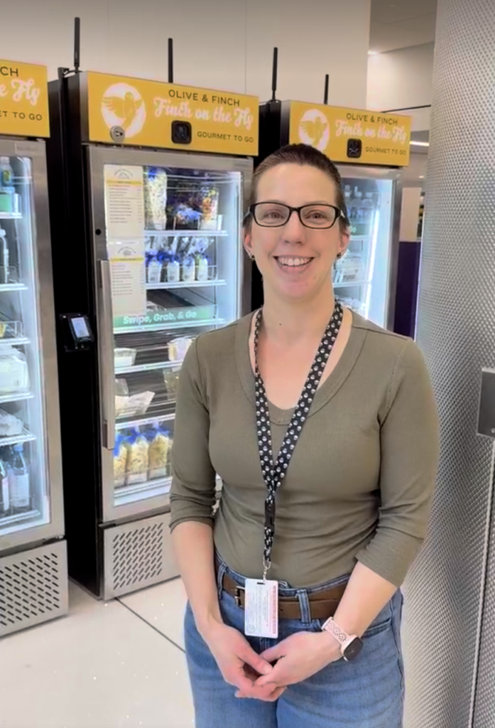 woman smiling standing in front of three fresh food vending machines